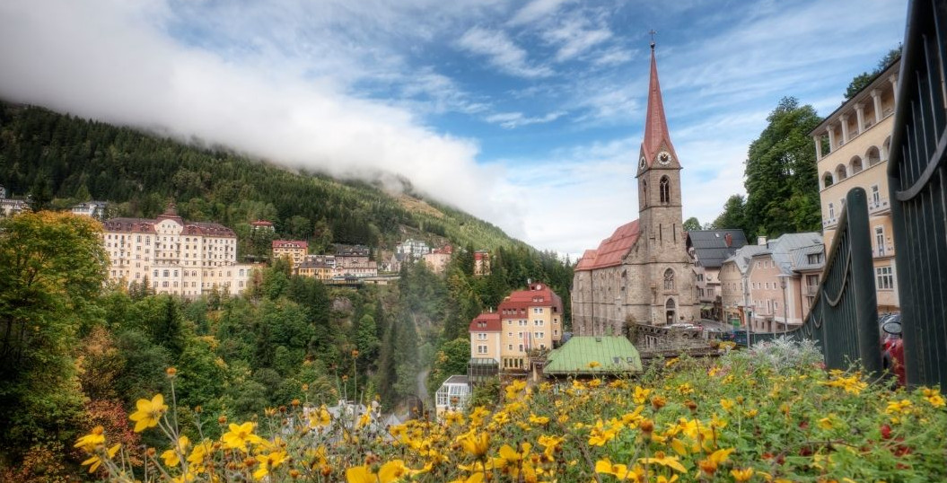 Bad Gastein by med kyrka, alpblommor i förgrunden